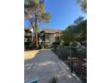 View of the exterior of a two-story townhouse and gated yard with mature trees at 520 Elm Dr # 202, Las Vegas, NV 89169