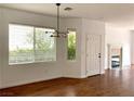 A sunlit living room featuring wood floors, a modern chandelier, and a cozy fireplace at 9236 Canalino Dr, Las Vegas, NV 89134