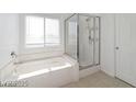Bathroom with bathtub, glass shower, and window for natural lighting at 9247 Tulip Trestle Ave, Las Vegas, NV 89148