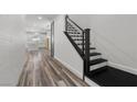 Hallway featuring wood floors, staircase with black banister and white kitchen at 9430 Isla Lee Ave, Las Vegas, NV 89178