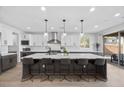 Bright, modern kitchen featuring a large island with bar seating, stainless steel appliances, and pendant lighting at 10470 Dove Meadow Way, Las Vegas, NV 89135