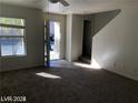Bright living room featuring neutral paint, carpet floors, ceiling fan, and access to stairs and a window at 11882 Snow Bank St, Las Vegas, NV 89183
