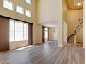 Bright, open living room with tall windows, wood laminate flooring, and staircase at 153 Cascade Lake St, Las Vegas, NV 89148