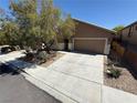 Tan single story house, concrete driveway, two car garage, and desert landscaping at 5019 Quiet Falls Ct, Las Vegas, NV 89141