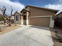Tan single story house, concrete driveway, two car garage, and desert landscaping at 5019 Quiet Falls Ct, Las Vegas, NV 89141