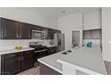 Modern kitchen featuring stainless steel appliances, quartz countertops, and dark wood cabinetry at 556 Decidedly St, Henderson, NV 89015