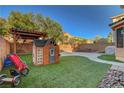 A well-manicured backyard with artificial grass, playhouse, patio cover, and privacy fence at 644 Mauna Kea Pl, Henderson, NV 89011