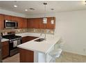 Modern kitchen with brown cabinets, stainless appliances, tile backsplash, and breakfast bar with pendant lights at 7461 Enviable Ct, Las Vegas, NV 89149