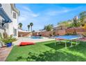 Expansive backyard featuring a pool, artificial turf, and outdoor game area at 7492 Midfield Ct, Las Vegas, NV 89120