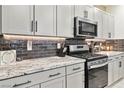 Modern kitchen with gray backsplash, stainless steel appliances, and granite countertops at 10190 Natural Anchor St, Las Vegas, NV 89166