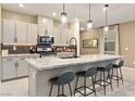 Spacious kitchen with island, seating, gray cabinets, stainless steel appliances and modern pendant lighting at 10190 Natural Anchor St, Las Vegas, NV 89166