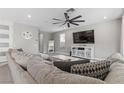 Bright living room with a large gray sectional sofa, modern ceiling fan, and stylish decor at 12413 Alpenglow Ct, Las Vegas, NV 89138