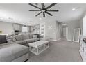 Open-concept living room with plush gray sofa, neutral decor, ceiling fan and access to the kitchen at 12413 Alpenglow Ct, Las Vegas, NV 89138