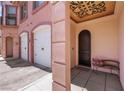 Inviting entryway with a decorative ceiling design, arched door, and a cozy bench with plush throw pillows at 30 Via Vasari # 102, Henderson, NV 89011