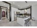 Modern kitchen featuring white cabinets, a marble-topped island with stools, stainless steel appliances, and dark backsplash at 30 Via Vasari # 102, Henderson, NV 89011