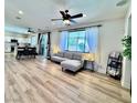 Bright living room featuring modern gray sofa, wood floors, and view into modern kitchen with dining area at 3194 Lapis Beach Dr, Las Vegas, NV 89117