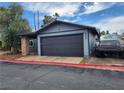 Single Gathering home featuring a dark painted garage and a tidy yard at 4745 Madrigal Way, Las Vegas, NV 89122
