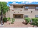 A two-story condo building with desert landscaping featuring green bushes and flowering pink plants at 7200 Pirates Cove Rd # 1011, Las Vegas, NV 89145