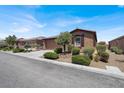 Single story home with desert landscaping and a tile roof, surrounded by lush, green shrubs at 7428 Alamo Ranch Ave, Las Vegas, NV 89179