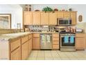 Functional kitchen featuring light wood cabinetry, stainless steel appliances, and granite countertops at 9921 Woodhouse Dr, Las Vegas, NV 89134