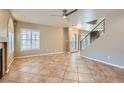 Open-concept living room featuring tile flooring, a ceiling fan, and a staircase at 10159 Tumbling Tree St, Las Vegas, NV 89183