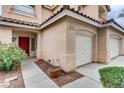 Home featuring a red door, desert landscaping and a two car garage at 1124 Coral Rainbow Ave, Las Vegas, NV 89123