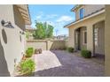 Beautiful brick paved patio featuring a high privacy wall, landscaping, and sconce lighting at 12273 Catanzaro Ave, Las Vegas, NV 89138