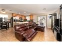 Inviting living room featuring tile flooring, a leather sofa set, and an open layout to the kitchen at 3120 Inlet Bay Ave, North Las Vegas, NV 89031