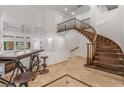 Welcoming foyer boasts travertine flooring, a winding staircase and soaring ceilings creating an airy ambiance at 56 Grossinger Ct, Henderson, NV 89074