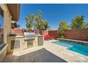 A covered outdoor kitchen featuring a built-in grill, next to a pool with lounge chairs at 5662 Oak Bend Dr, Las Vegas, NV 89135