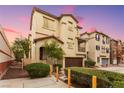 The exterior of a tan two-story townhome featuring an attached garage and small front yard at 6488 Bentley Wood Ct, Las Vegas, NV 89130