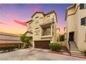 Exterior view of a stucco townhome with a brown garage door and well-kept landscaping at 6488 Bentley Wood Ct, Las Vegas, NV 89130