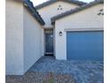 Home's front entrance and attached two car garage with a blue door at 73 Hawk Ave, Pahrump, NV 89060