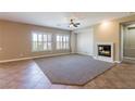 Bright living room featuring a cozy fireplace, tile and carpet flooring and white shuttered windows at 7434 Eggshell Dr, North Las Vegas, NV 89084