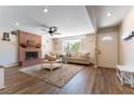 Cozy living room with brick fireplace, wood floors, and natural light from the bay window at 100 Walker Way, Boulder City, NV 89005