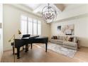 Elegant living room features a piano, modern chandelier, and large windows at 10002 Trapper Mountain St, Las Vegas, NV 89178