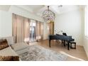 Bright living room with a piano, modern chandelier, and patio access at 10002 Trapper Mountain St, Las Vegas, NV 89178