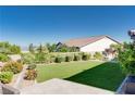 Private backyard with artificial lawn, mature trees, and manicured shrubs at 12168 Dorada Coast Ave, Las Vegas, NV 89138