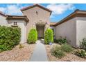 Home's beautiful front entrance with stone archway, lush green plants, and easy to maintain desert landscaping at 2244 Shadow Canyon Dr, Henderson, NV 89044