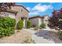 Close-up of the home's front entrance featuring a stone archway, desert landscaping, and manicured shrubbery at 2244 Shadow Canyon Dr, Henderson, NV 89044
