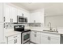 Bright kitchen featuring stainless steel appliances, white cabinetry and stone backsplash at 3150 Soft Breezes Dr # 1037, Las Vegas, NV 89128