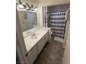 Well-lit bathroom featuring wood-style flooring, a white vanity, and a shower with a decorative striped curtain at 4820 Mahogany Dr, Las Vegas, NV 89110