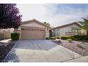 Inviting single-story home with a two-car garage, a driveway, and desert landscaping at 66 Sunset Bay St, Las Vegas, NV 89148