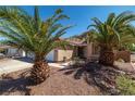 Attractive single-story home featuring desert landscaping and mature palm trees at 688 Arrowhead Canyon Dr, Henderson, NV 89002