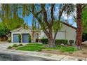 Beautiful single-story home featuring a stone facade, well-manicured lawn, and mature shade trees at 729 Sir James Bridge Way, Las Vegas, NV 89145