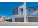 Eye-level view of two-story modern homes with minimalist exteriors and attached garages on a sunny day at 9756 Rock Cliff St, Las Vegas, NV 89141
