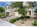 Lovely home with a two-car garage, stone accents, a paved driveway, and beautiful green landscaping at 10512 Mann St, Las Vegas, NV 89141