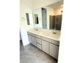 Well-lit bathroom featuring a double vanity with gray cabinets, quartz countertops, and a framed mirror at 11423 Ethereal Landing Ave, Las Vegas, NV 89138