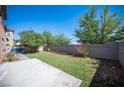 Spacious backyard featuring artificial turf, a concrete patio, and mature trees at 1405 Gilbert Creek Ave, North Las Vegas, NV 89031