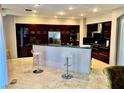 This gourmet kitchen has dark wood cabinets, stainless appliances, and an expansive center island with bar stool seating at 1915 Hazeltine Ct, Henderson, NV 89074